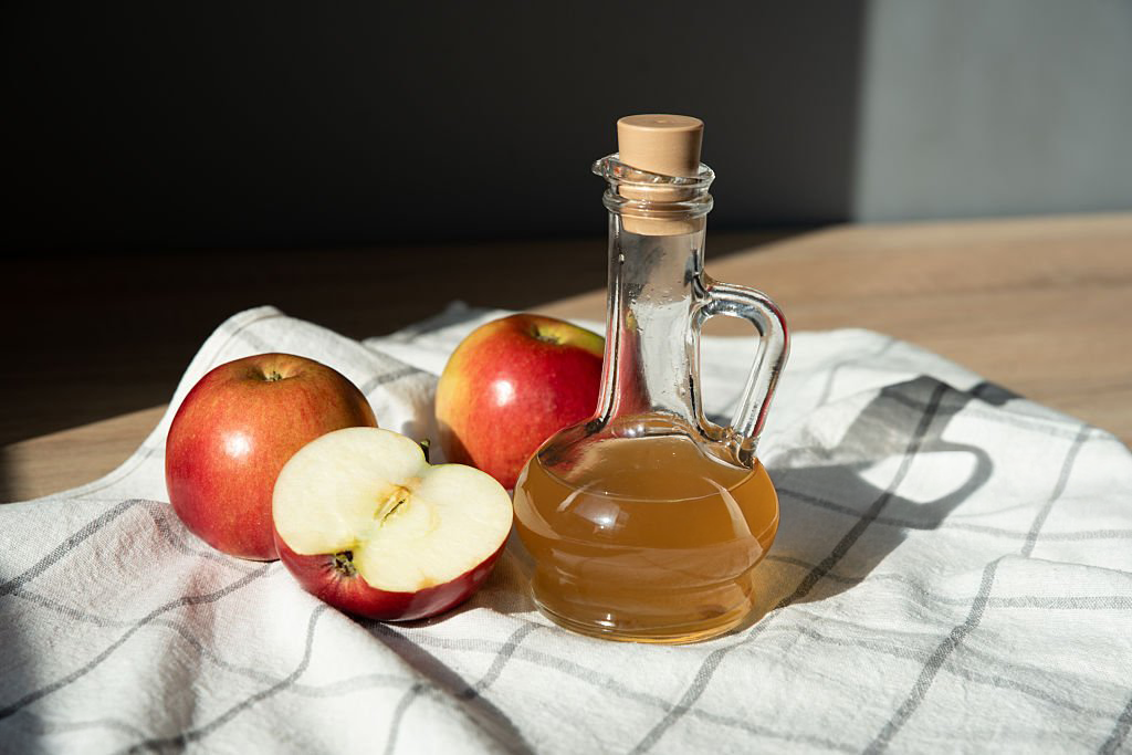 botella con vinagre y manzanas al rededor